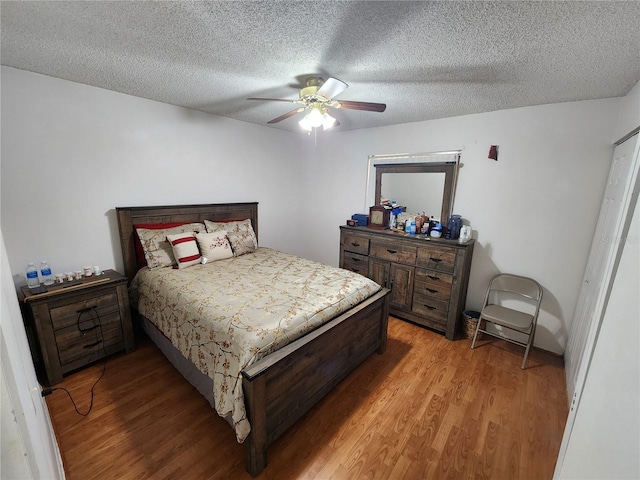 bedroom with ceiling fan, light hardwood / wood-style floors, and a textured ceiling