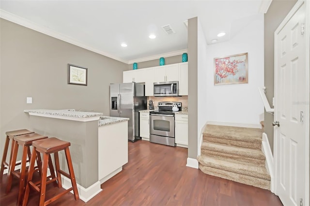 kitchen featuring stainless steel appliances, kitchen peninsula, crown molding, a kitchen bar, and white cabinets