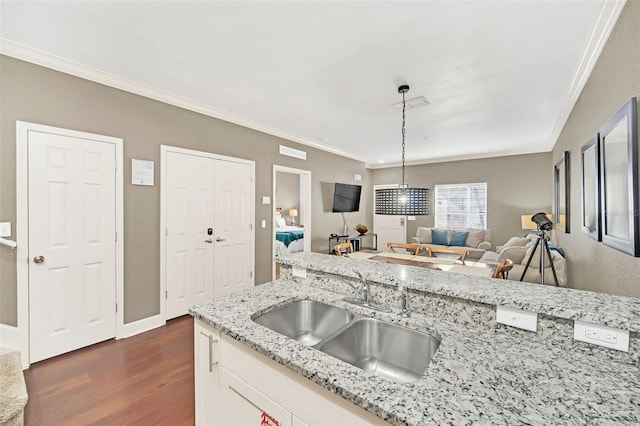 kitchen featuring white cabinets, sink, hanging light fixtures, ornamental molding, and light stone counters