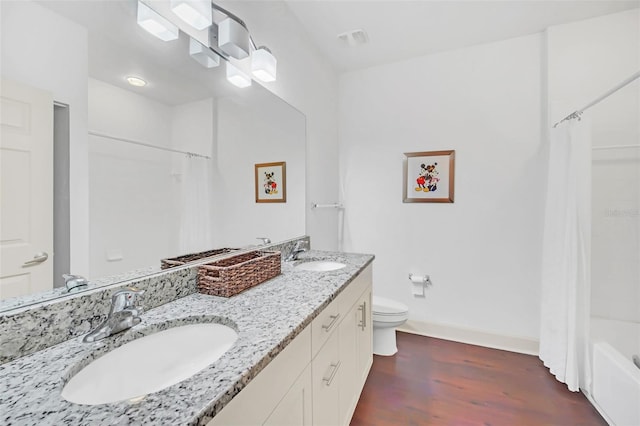 full bathroom with hardwood / wood-style floors, vanity, shower / bath combo, and toilet