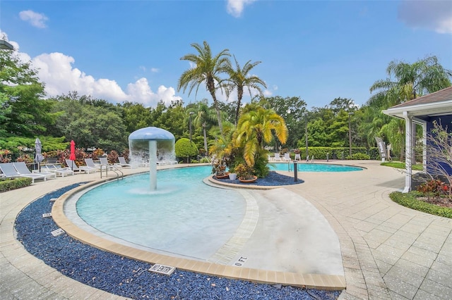 view of swimming pool with pool water feature and a patio area