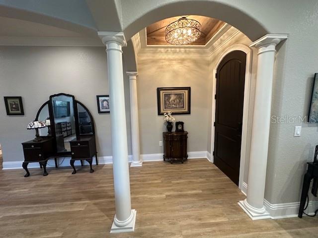 hallway featuring a chandelier, light wood-type flooring, and ornamental molding