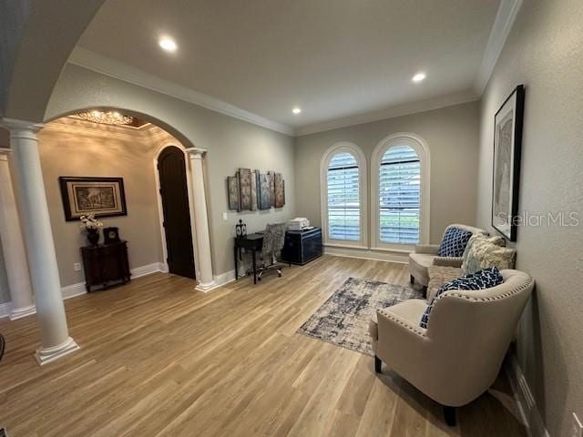 living area featuring decorative columns, crown molding, and light wood-type flooring