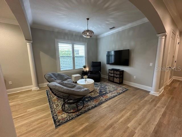 living room with ornate columns, light hardwood / wood-style floors, and ornamental molding