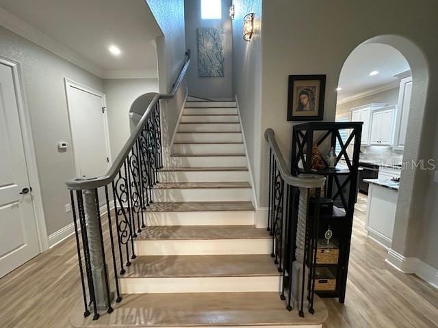 stairs featuring wood-type flooring and ornamental molding