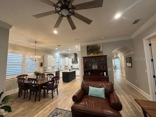 dining space featuring ceiling fan with notable chandelier, ornamental molding, and light hardwood / wood-style flooring