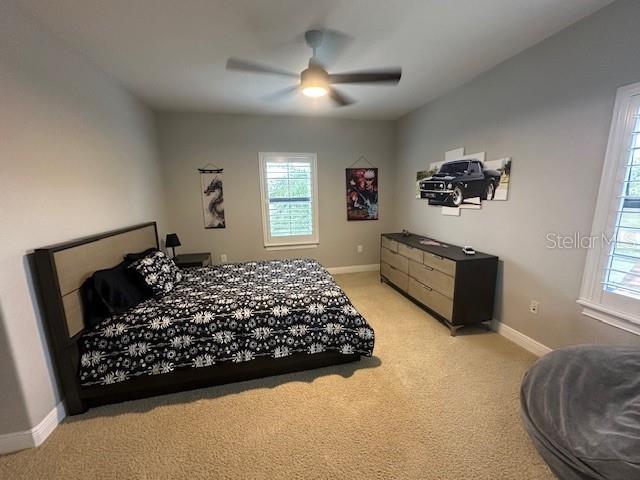 bedroom with ceiling fan and light colored carpet