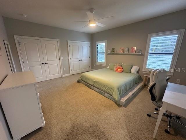 carpeted bedroom featuring ceiling fan and two closets