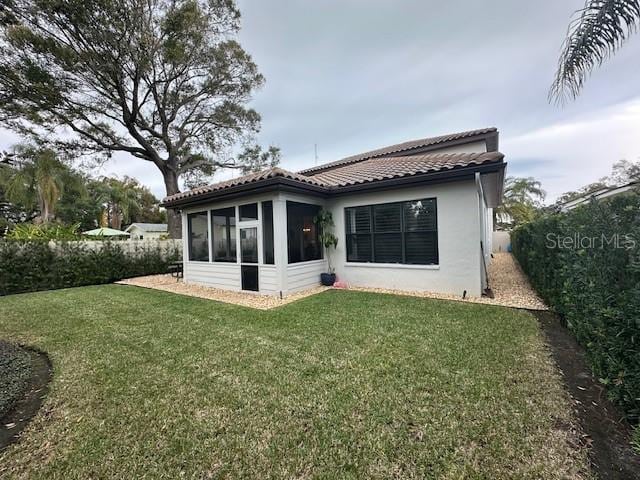 back of property with a sunroom and a yard