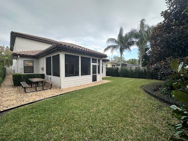 rear view of property featuring a sunroom and a yard