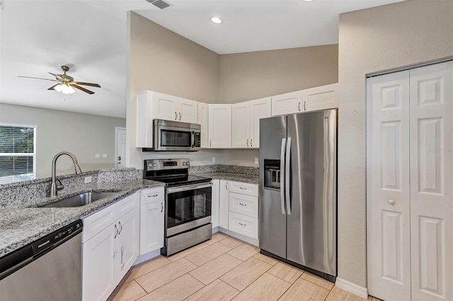 kitchen with sink, stainless steel appliances, white cabinetry, and light stone countertops