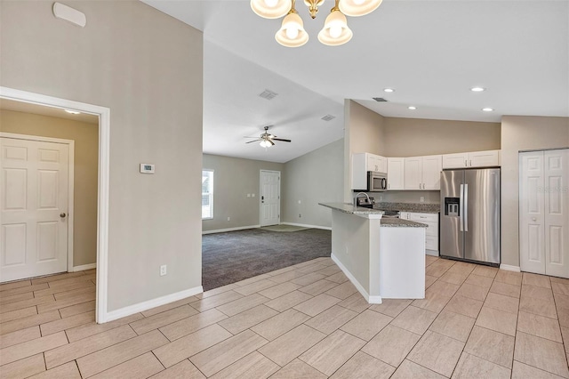 kitchen with white cabinetry, light stone counters, kitchen peninsula, ceiling fan with notable chandelier, and appliances with stainless steel finishes