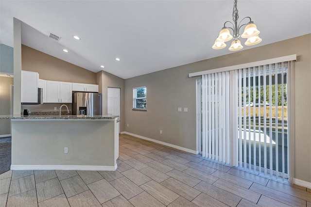 kitchen with vaulted ceiling, a notable chandelier, pendant lighting, stainless steel refrigerator with ice dispenser, and white cabinets