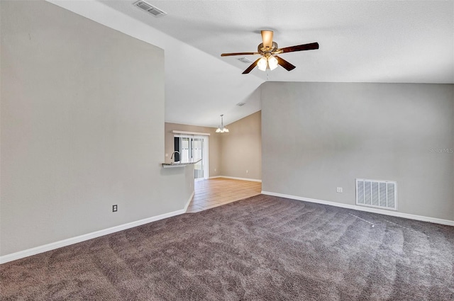 unfurnished living room featuring ceiling fan with notable chandelier, carpet floors, and vaulted ceiling