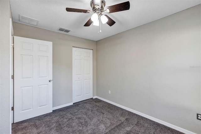 unfurnished bedroom with ceiling fan, a closet, and dark colored carpet