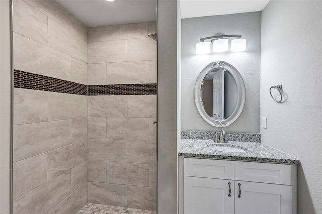 bathroom featuring tiled shower and vanity