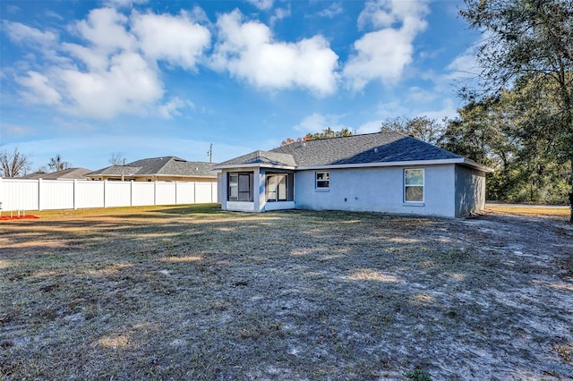 rear view of house featuring a lawn and a sunroom