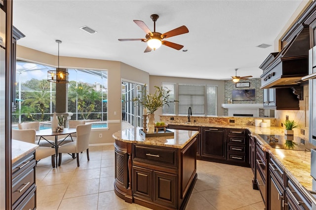 kitchen with dark brown cabinets, hanging light fixtures, light tile patterned floors, and sink