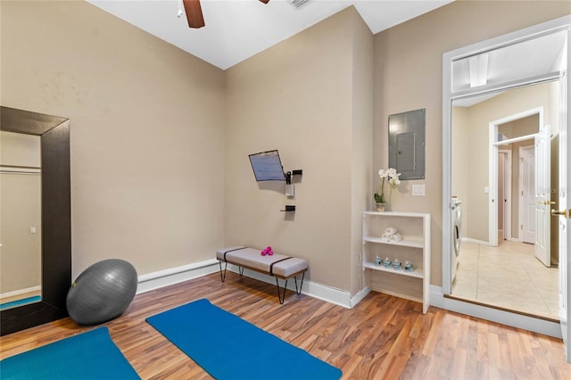 exercise area featuring electric panel, light wood-type flooring, ceiling fan, and washer / dryer