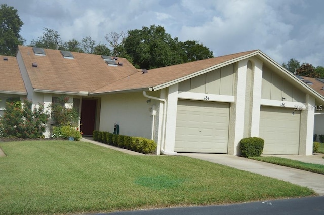 view of property with an attached garage, a front lawn, board and batten siding, and roof with shingles