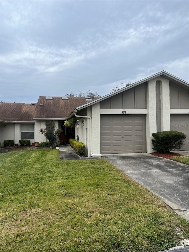 view of front facade featuring driveway, stucco siding, an attached garage, and a front yard