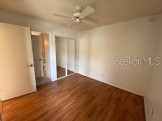 unfurnished bedroom featuring a closet, wood finished floors, and a ceiling fan