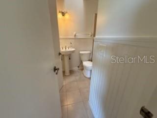 half bathroom with a sink, toilet, and tile patterned floors