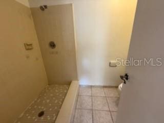 bathroom featuring a shower, toilet, and tile patterned floors