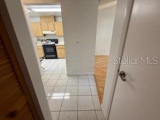 hall featuring baseboards and light tile patterned floors