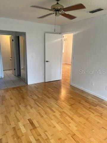 empty room featuring visible vents, ceiling fan, and light wood-style flooring