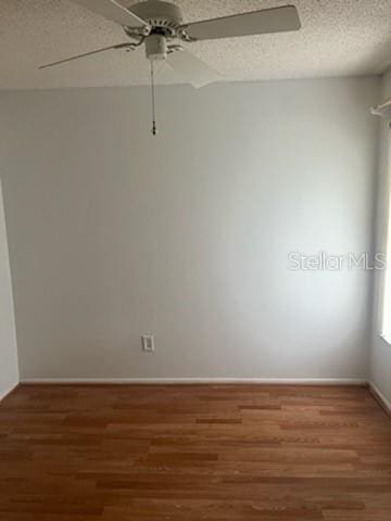 unfurnished room featuring dark wood-type flooring, a textured ceiling, and a ceiling fan