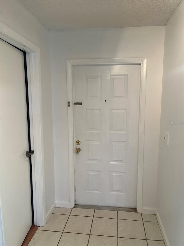 doorway to outside with baseboards and light tile patterned floors