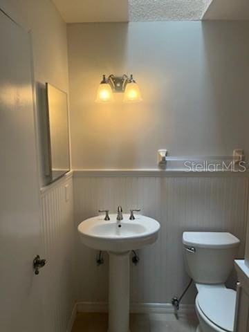 half bathroom with toilet and wainscoting