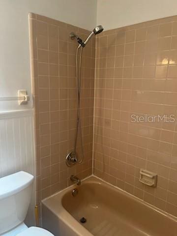 full bath with wainscoting, shower / bathing tub combination, and toilet