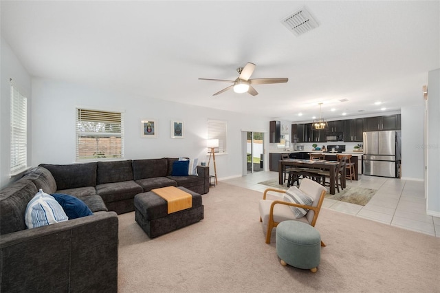 living room with light carpet, a wealth of natural light, and ceiling fan with notable chandelier