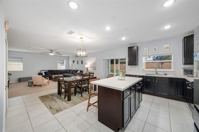 kitchen featuring sink, a kitchen island, light tile patterned floors, and decorative light fixtures