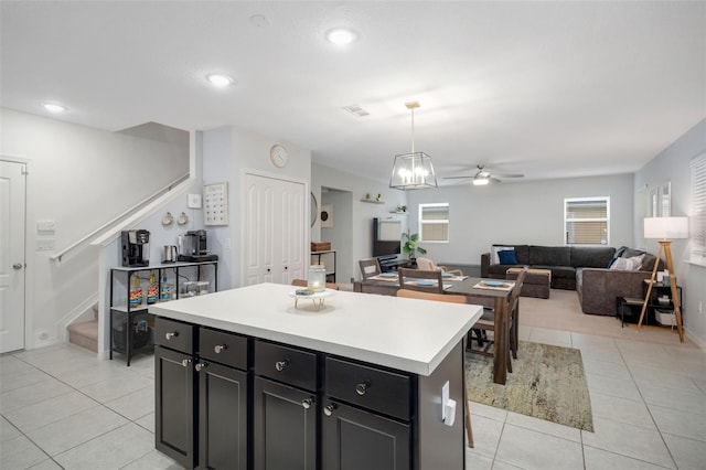 kitchen with ceiling fan, a kitchen island, decorative light fixtures, and light tile patterned floors