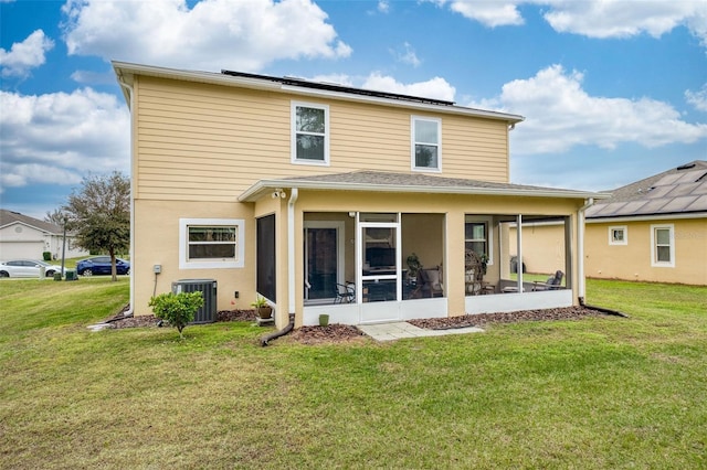 rear view of property featuring a lawn, solar panels, central AC unit, and a sunroom