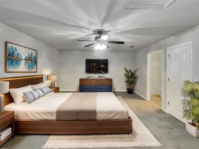 bedroom featuring light carpet, ensuite bathroom, and ceiling fan