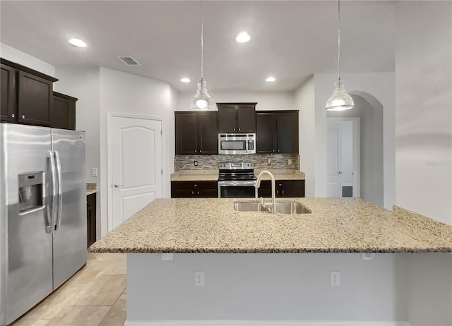 kitchen with sink, stainless steel appliances, tasteful backsplash, pendant lighting, and dark brown cabinets