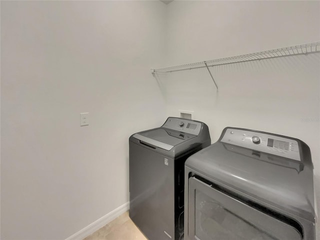 clothes washing area with washer and clothes dryer and light tile patterned floors