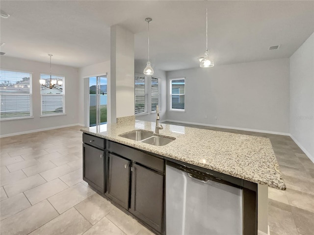 kitchen with dishwasher, a center island with sink, sink, hanging light fixtures, and light stone counters