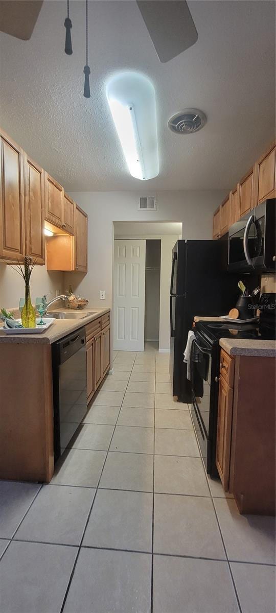 kitchen featuring sink, a textured ceiling, black appliances, and light tile patterned flooring