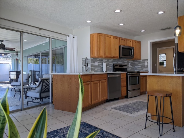 kitchen with decorative backsplash, a healthy amount of sunlight, light tile patterned floors, and appliances with stainless steel finishes