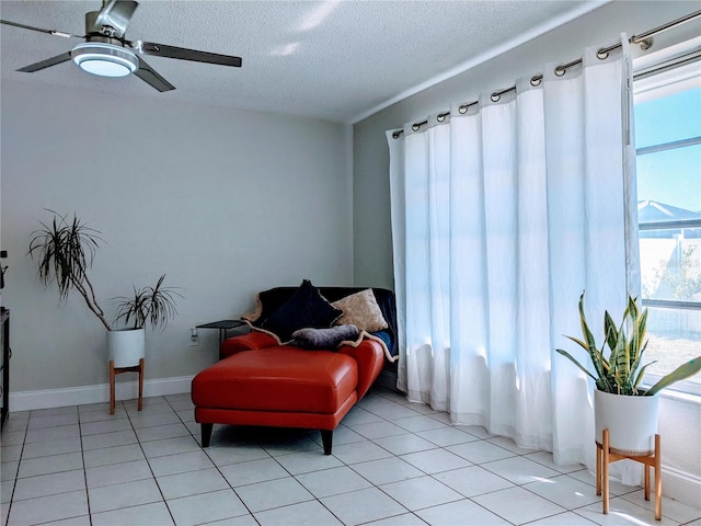 living area featuring a textured ceiling, ceiling fan, and light tile patterned flooring