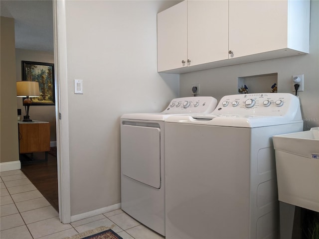 laundry room with washing machine and dryer, sink, light tile patterned floors, and cabinets