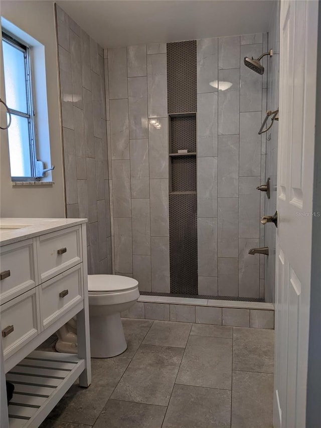 bathroom with tiled shower, vanity, and toilet