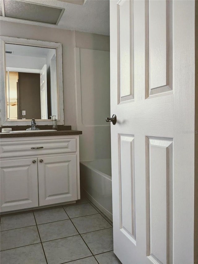 bathroom with a tub, tile patterned flooring, and vanity