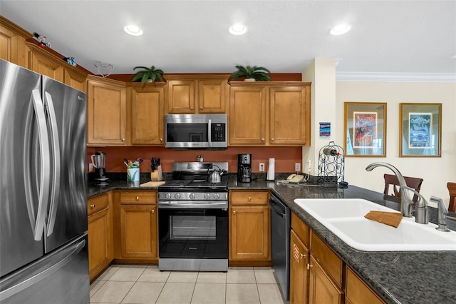 kitchen with sink, crown molding, dark stone countertops, stainless steel appliances, and light tile patterned flooring