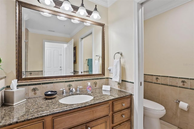 bathroom with tile walls, vanity, crown molding, and toilet